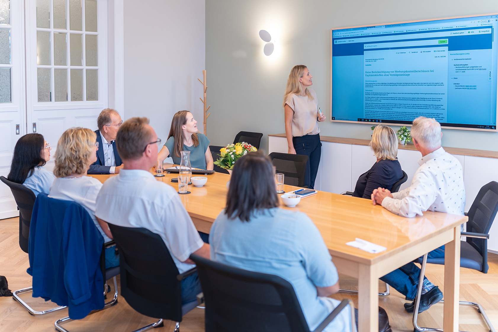 Mitarbeitende der Rose Treuhand GmbH sitzen im Besprechungsraum und verfolgen eine Präsentation auf großem Bildschirm.